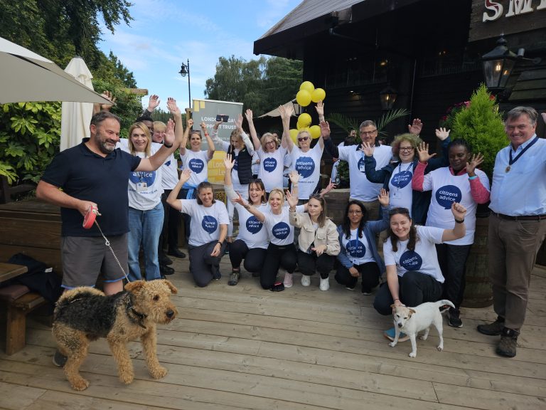 Citizens Advice in West Sussex team all wearing white T-Shirts with the Citizens Advice logo looking at the camera cheering